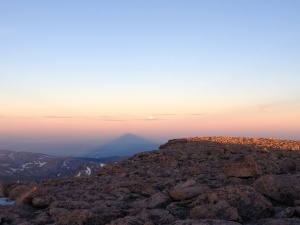 The shadow of Longs below the full moon at sunrise.